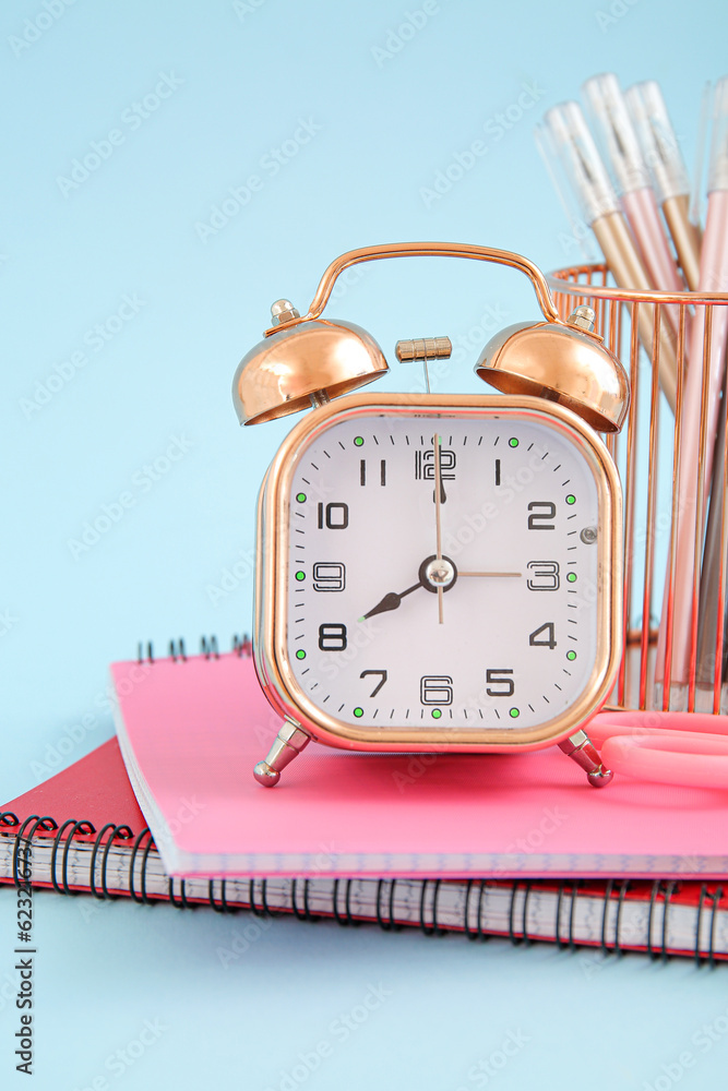 Alarm clock with different stationery on blue background