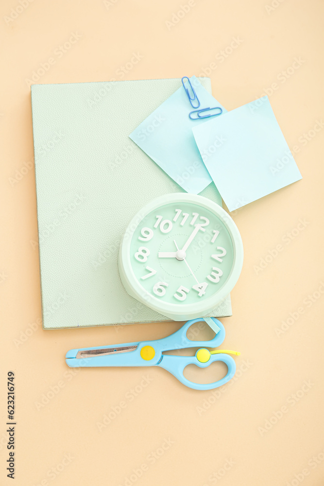 Alarm clock with different stationery on pale orange background