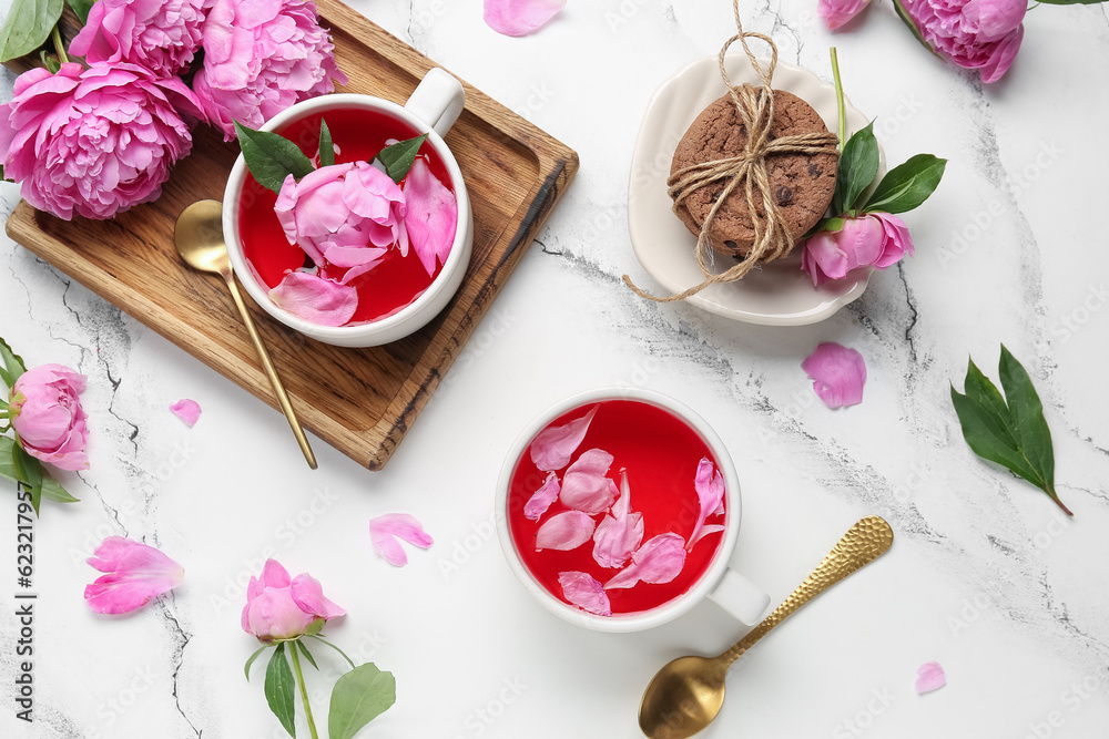 Composition with cups of tea, cookies and beautiful peony flowers on light background