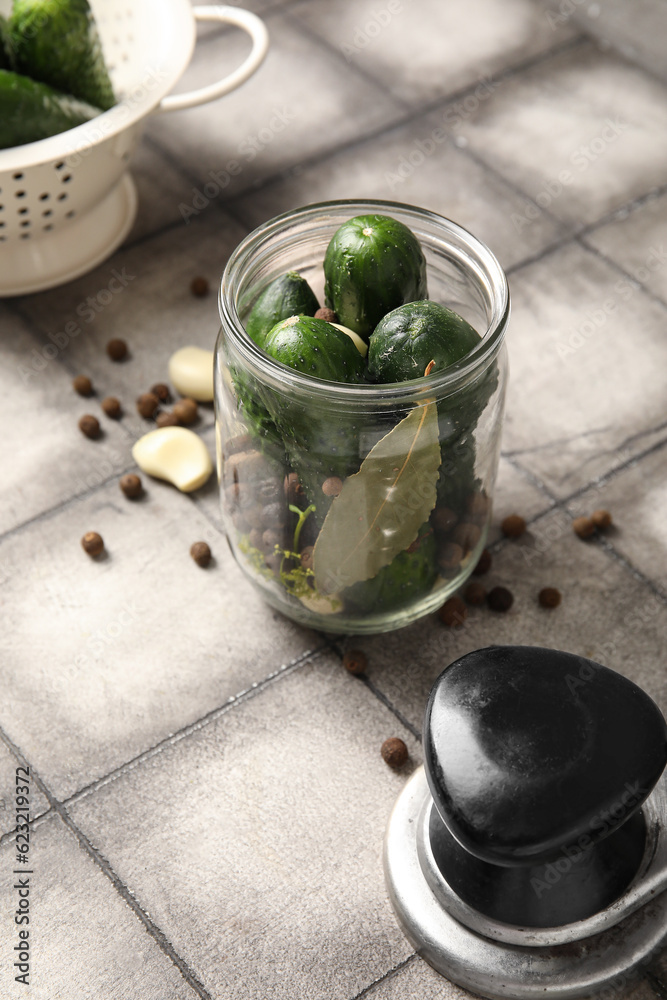 Jar with fresh cucumbers for preservation on grey tile background