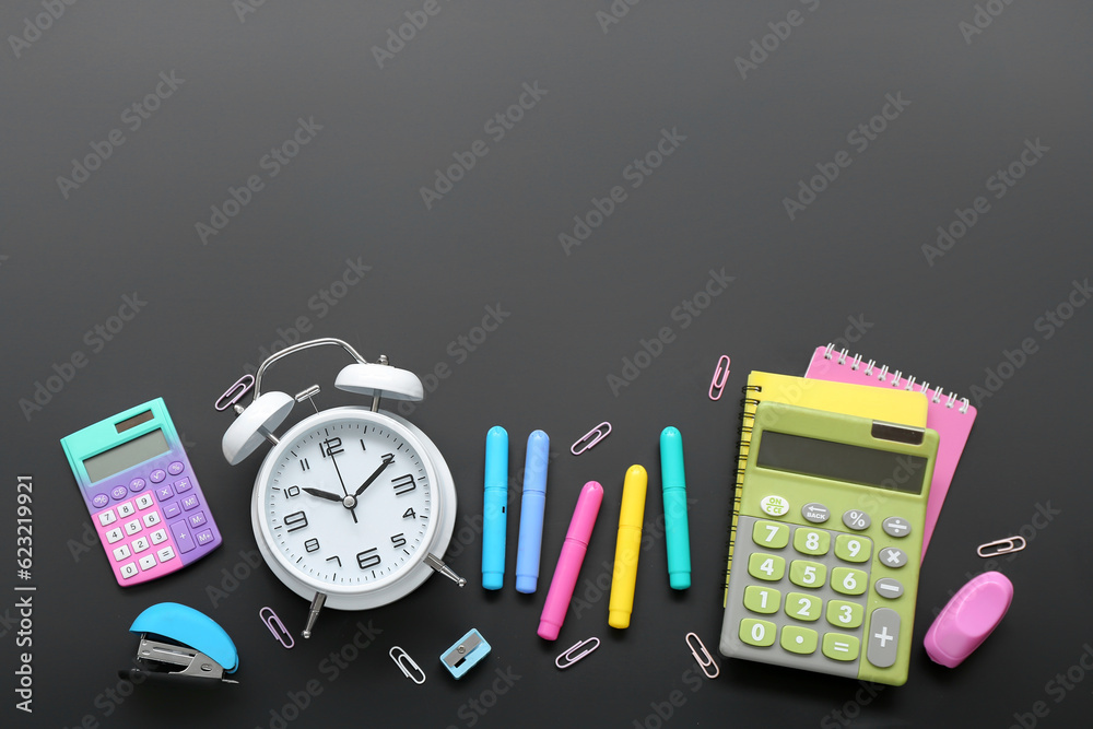 Alarm clock with calculators and different stationery on black chalkboard