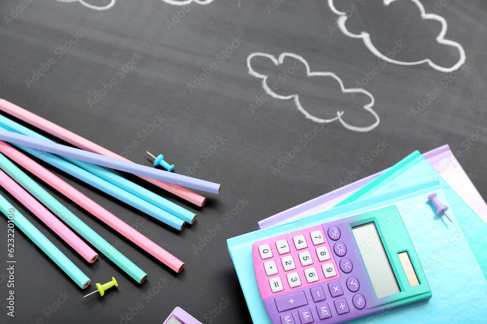 Drawn clouds with different stationery on black chalkboard