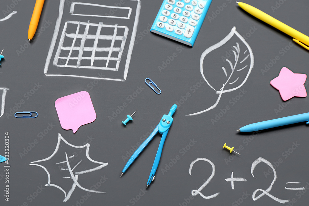 Different stationery and drawings on black chalkboard