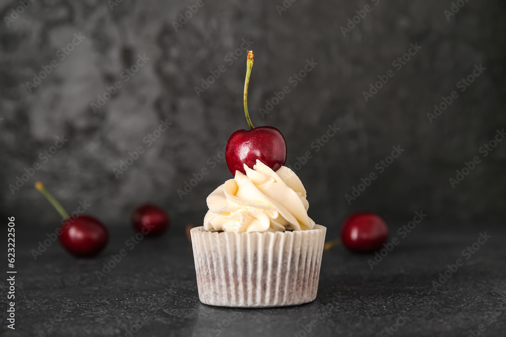 Tasty cherry cupcake on black background