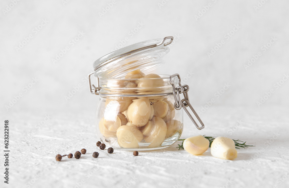 Jar with canned mushrooms on light background