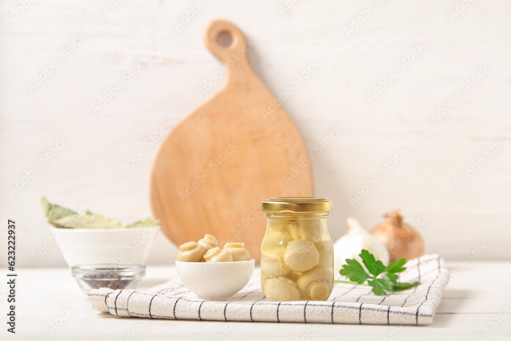 Jar and bowl with canned mushrooms on table