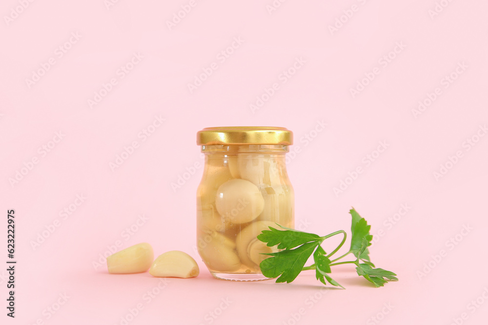 Jar with canned mushrooms on pink background