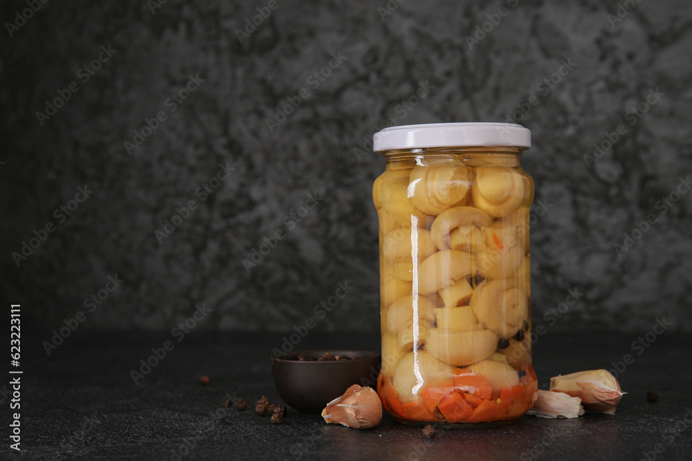 Jar with canned mushrooms on black background