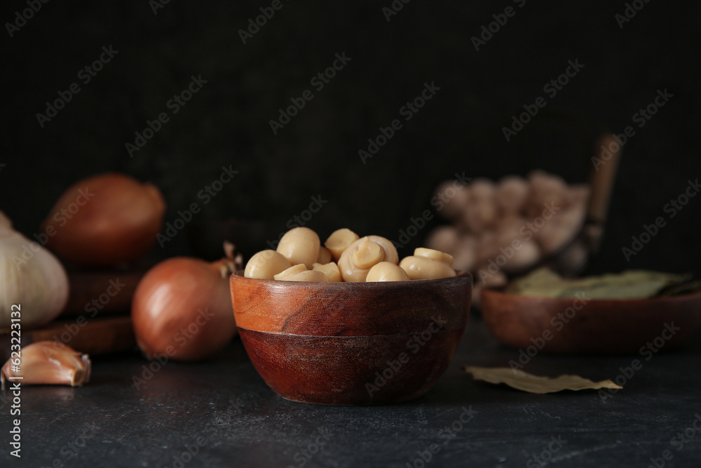 Bowl with canned mushrooms on black background