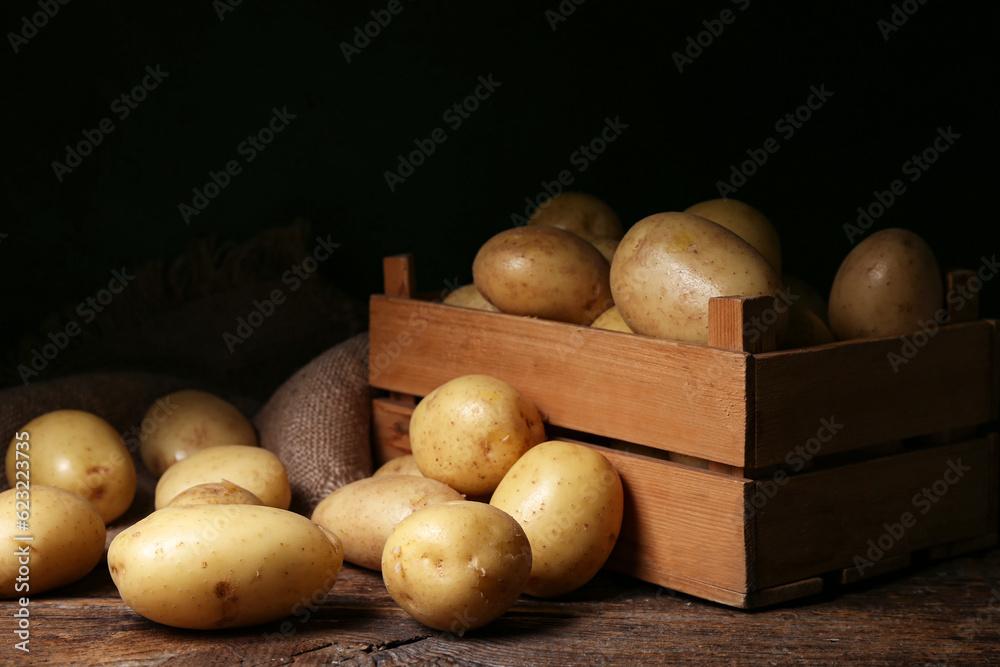 Box with raw potatoes on wooden table