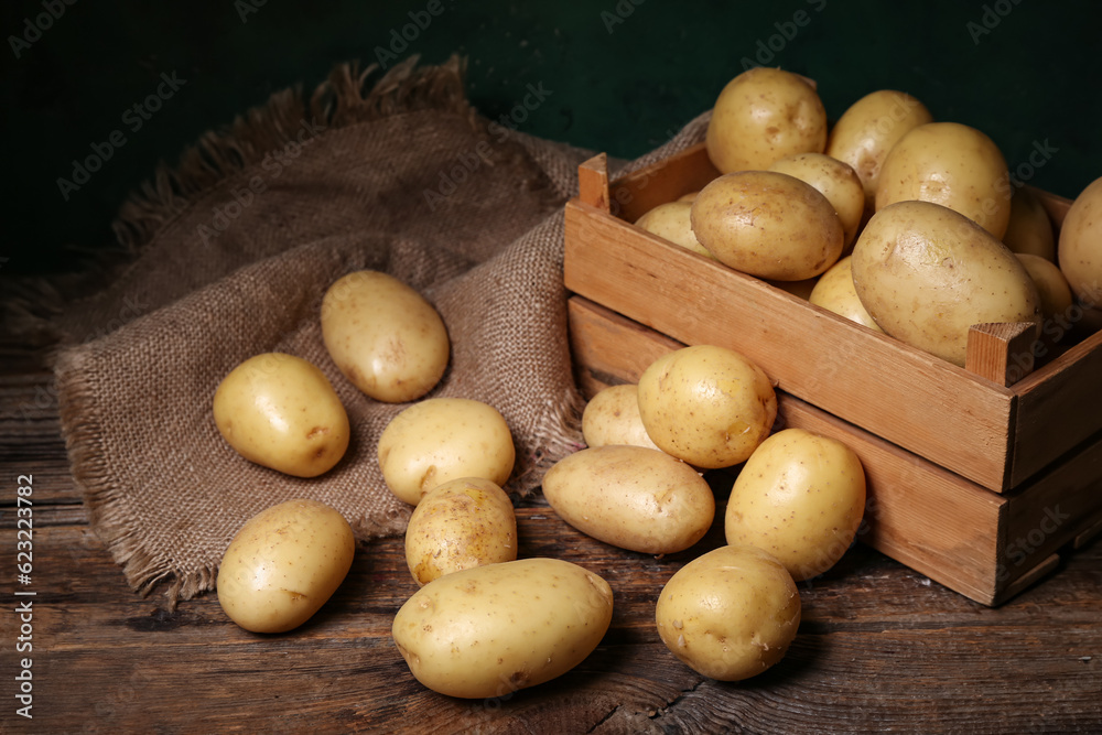 Box with raw potatoes on wooden table