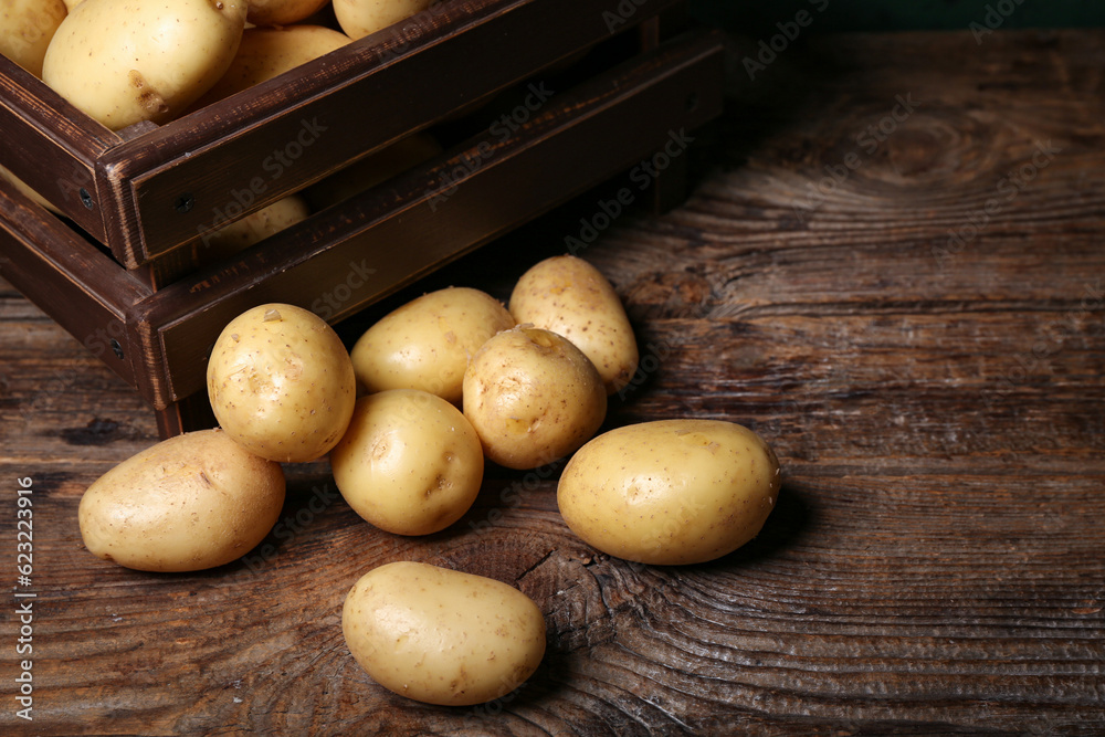 Box with raw potatoes on wooden table