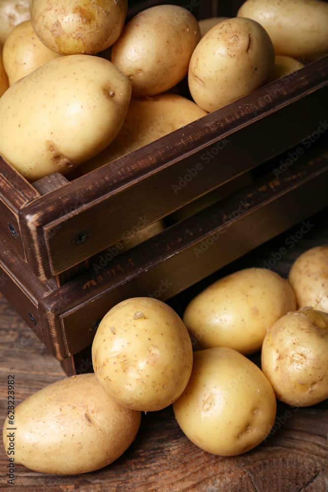 Box with raw potatoes on wooden table