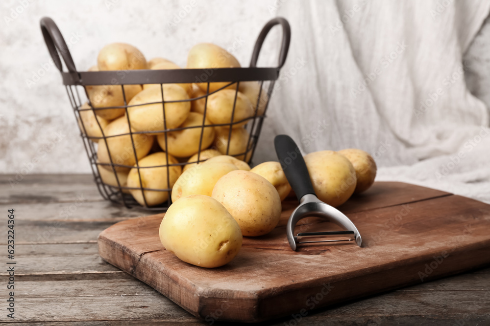 Board and basket with raw potatoes on wooden table