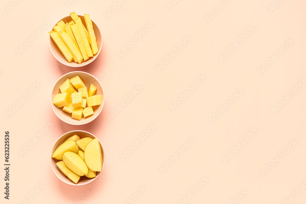 Bowls with pieces of raw potato on pink background