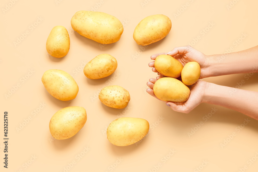 Woman holding raw potatoes on yellow background