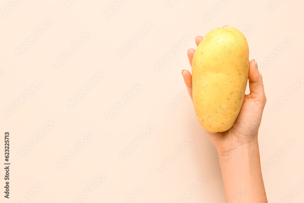 Woman holding raw potato on yellow background