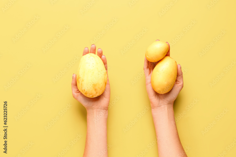 Woman holding raw potatoes on yellow background