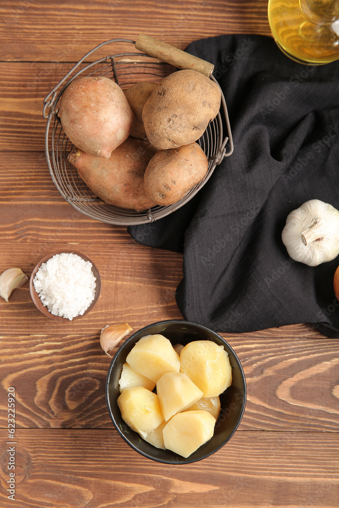 Boiled and raw potatoes on wooden background