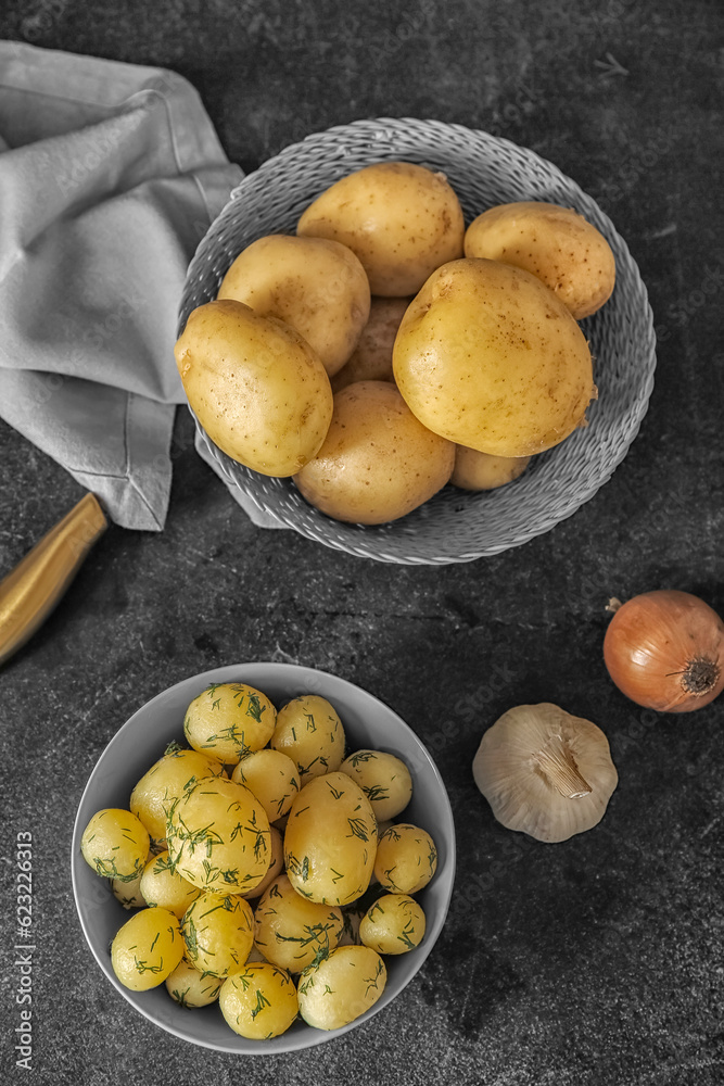 Boiled and raw baby potatoes on black background