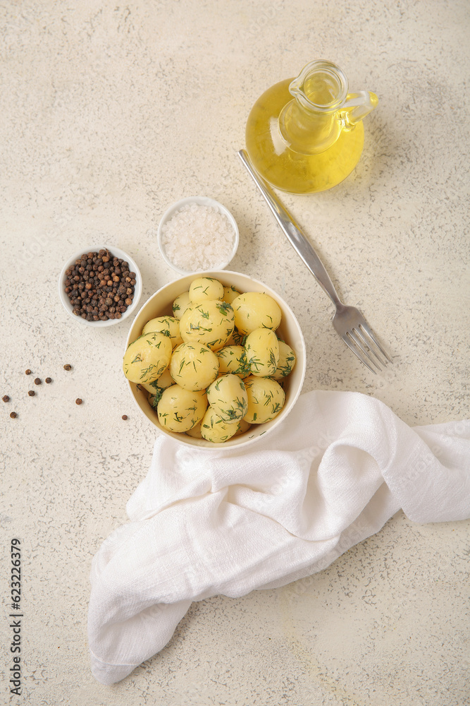 Bowl with boiled baby potatoes on light background