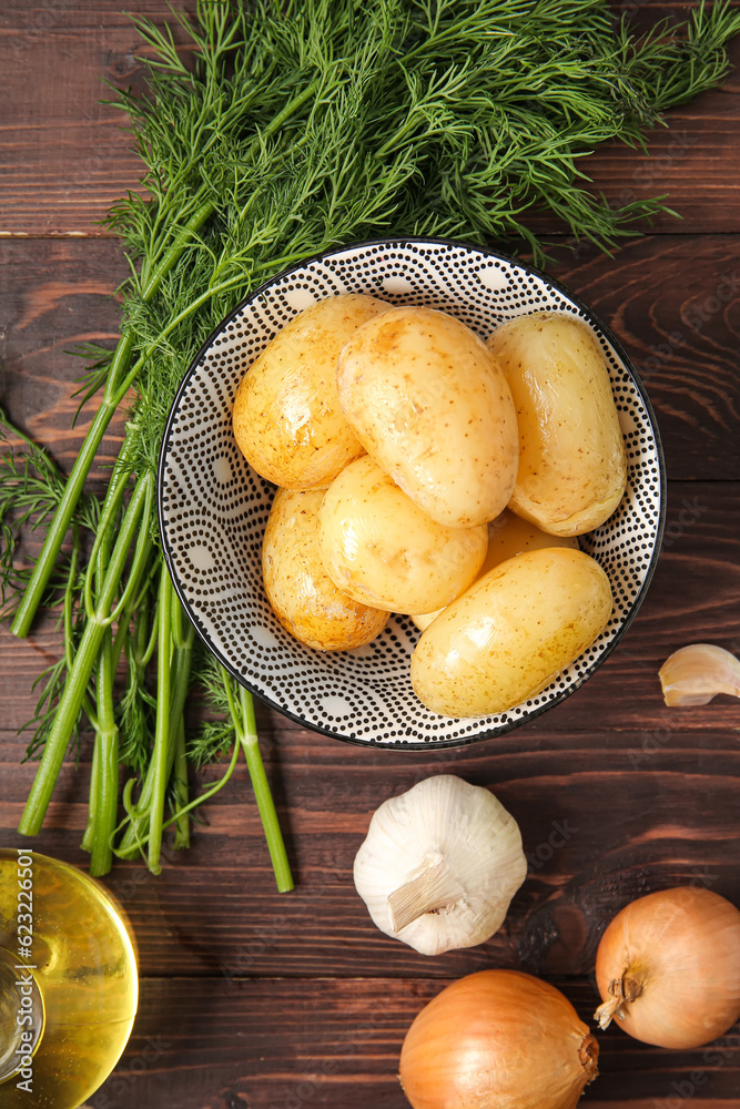 Bowl with raw potatoes on wooden background