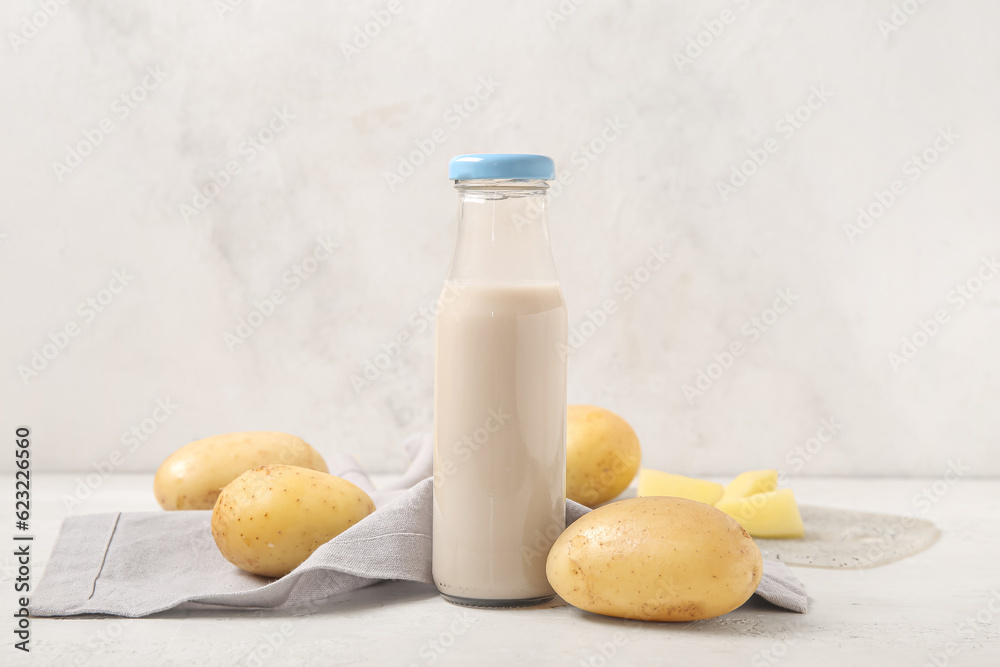 Bottle of tasty potato milk on light background