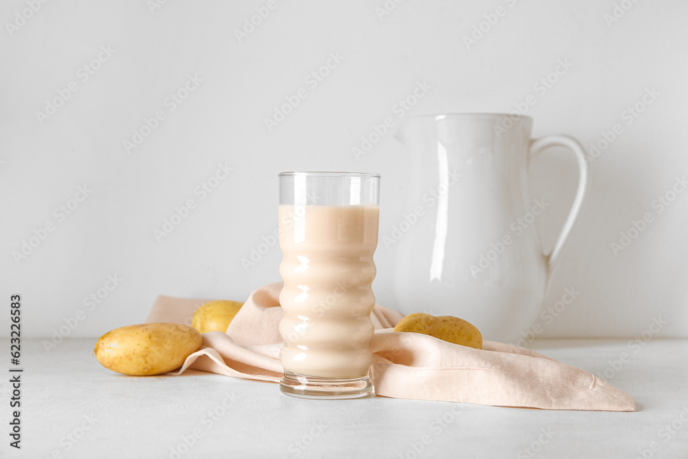 Glass of tasty potato milk on light background