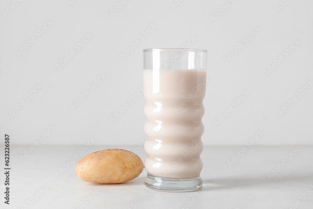 Glass of tasty potato milk on light background