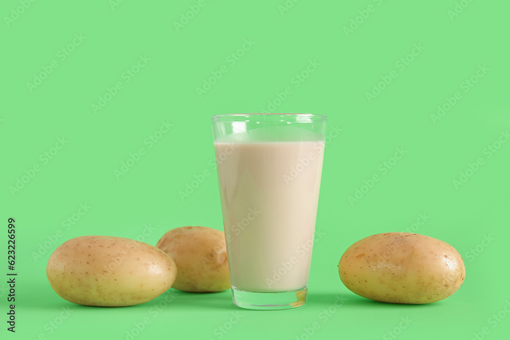 Glass of tasty potato milk on green background