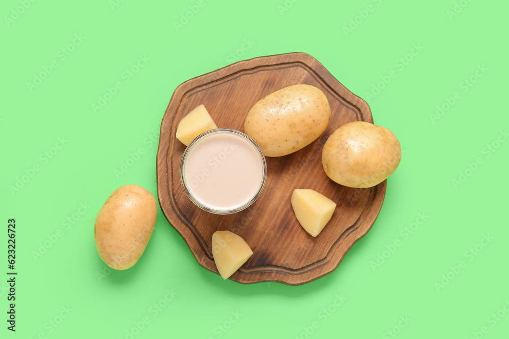 Glass of tasty potato milk on green background