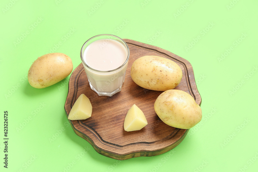 Glass of tasty potato milk on green background