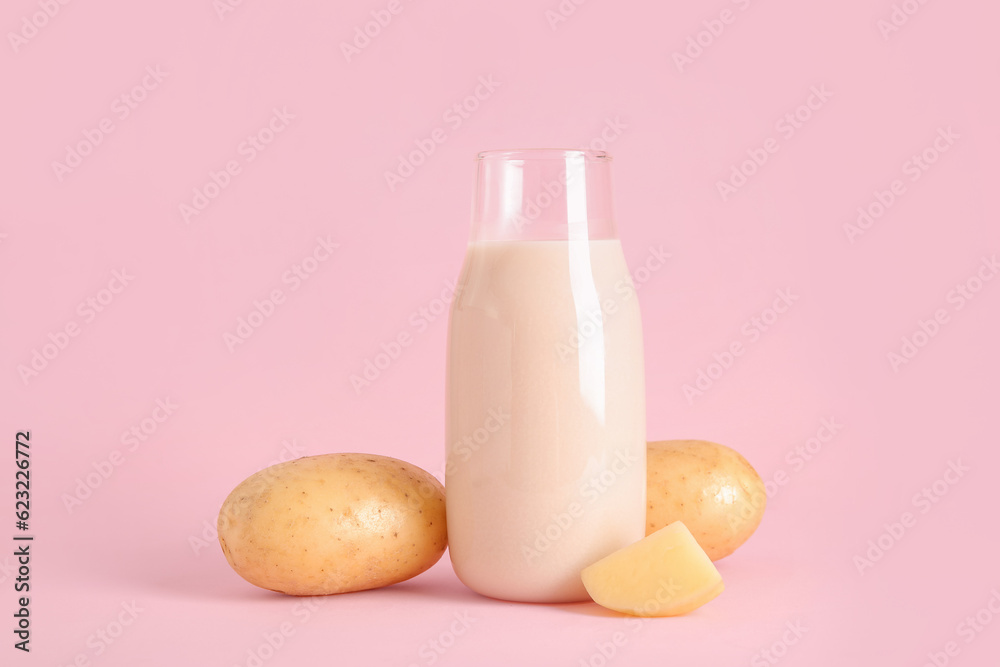 Bottle of tasty potato milk on pink background