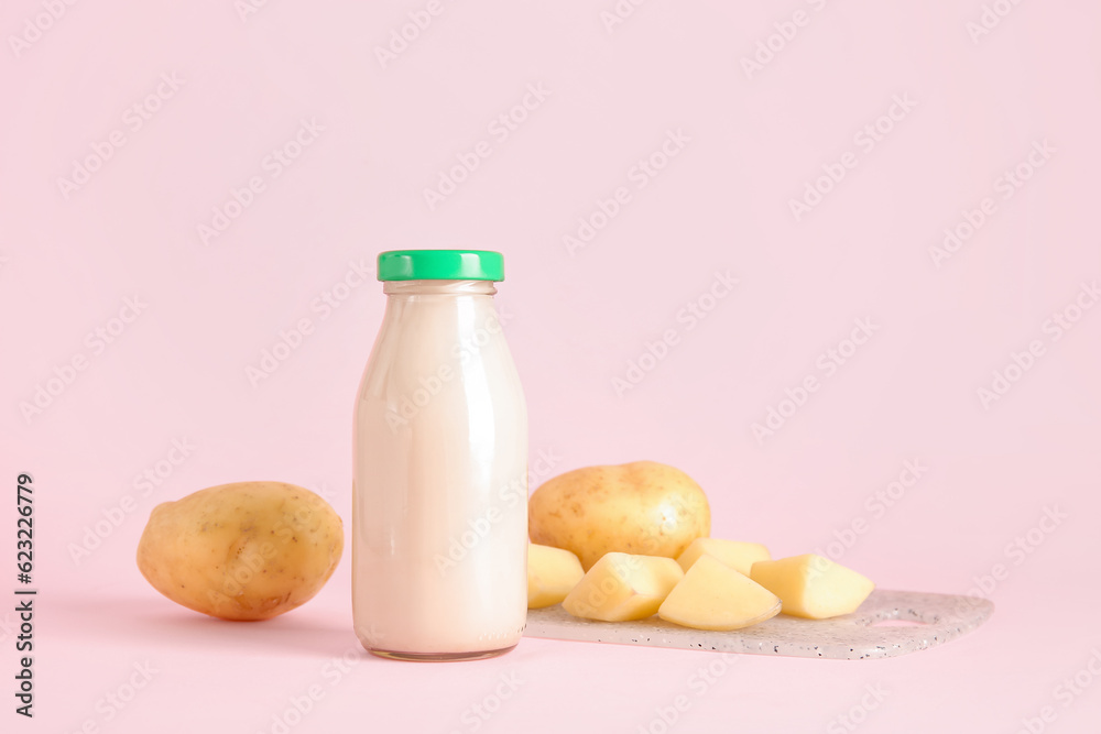 Bottle of tasty potato milk on pink background