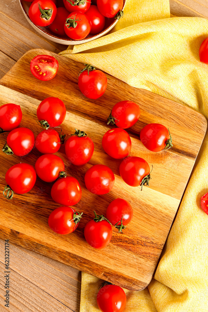 Board and bowl with fresh cherry tomatoes on wooden table