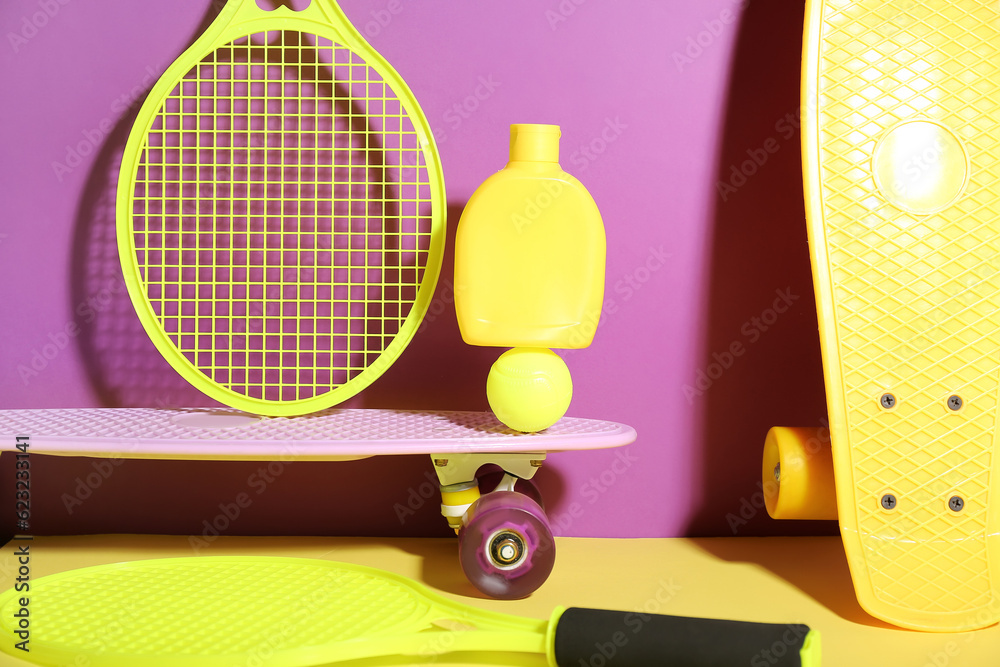 Composition with bottle of sunscreen cream, skateboards, tennis rackets and ball on color background