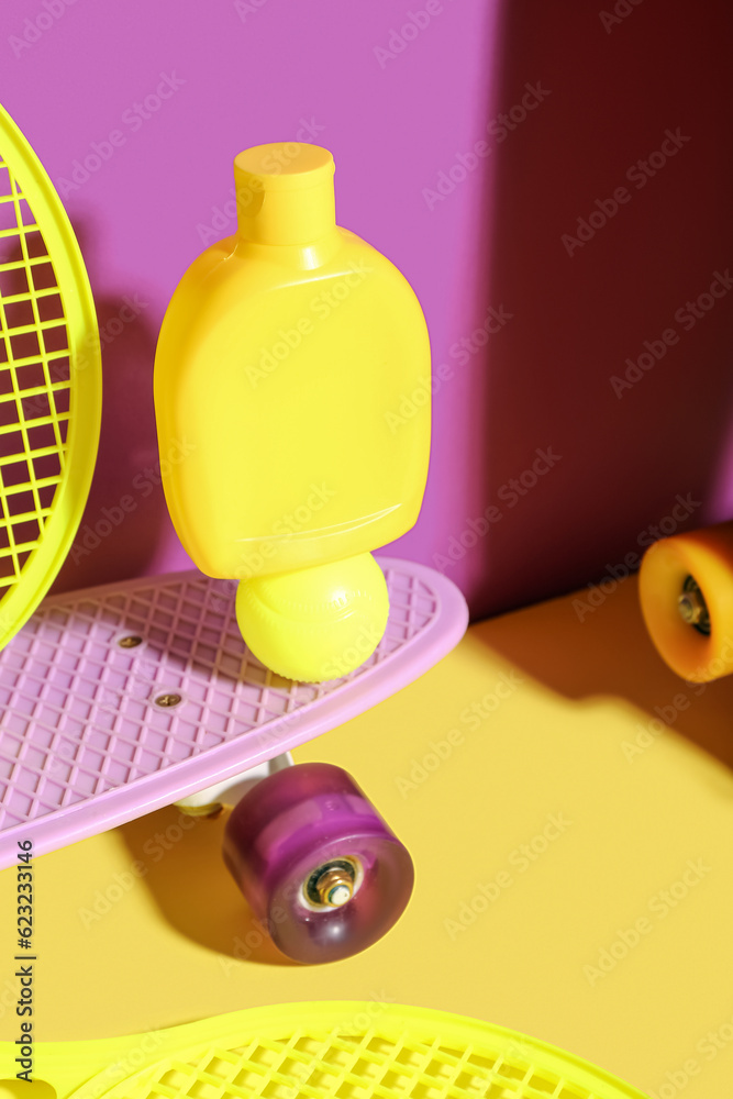 Composition with bottle of sunscreen cream, skateboard, tennis rackets and ball on color background