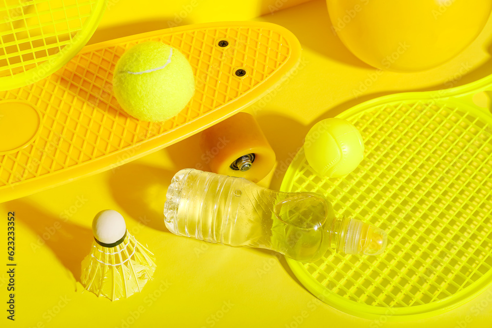 Set of sports equipment with bottle of water on yellow background