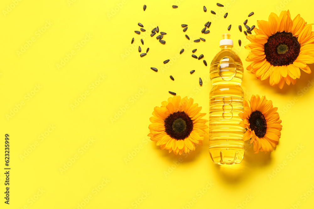 Sunflowers, seeds and bottle of oil on yellow background