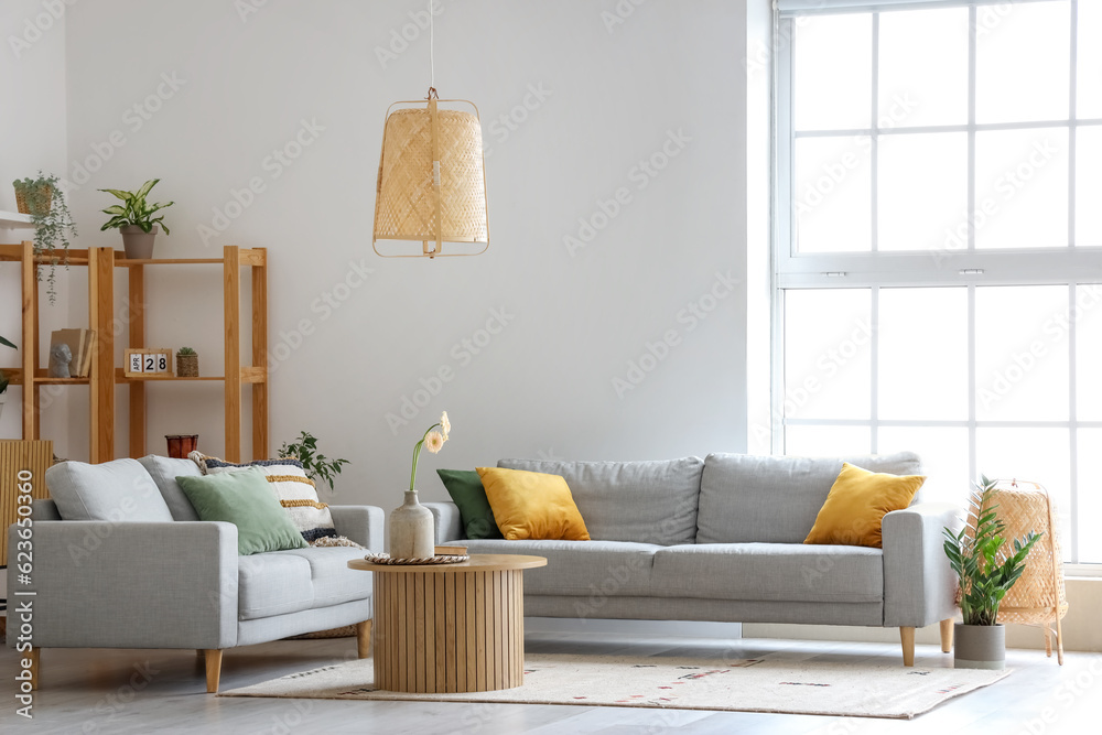 Interior of light living room with grey sofas, wooden coffee table and big window