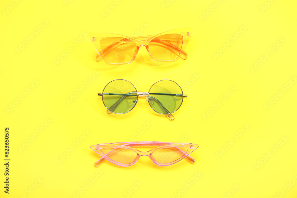 Different stylish sunglasses on yellow background