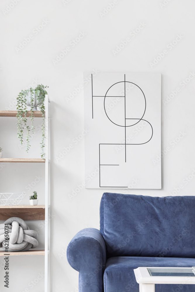 Interior of stylish living room with cozy blue sofa, poster and shelving unit