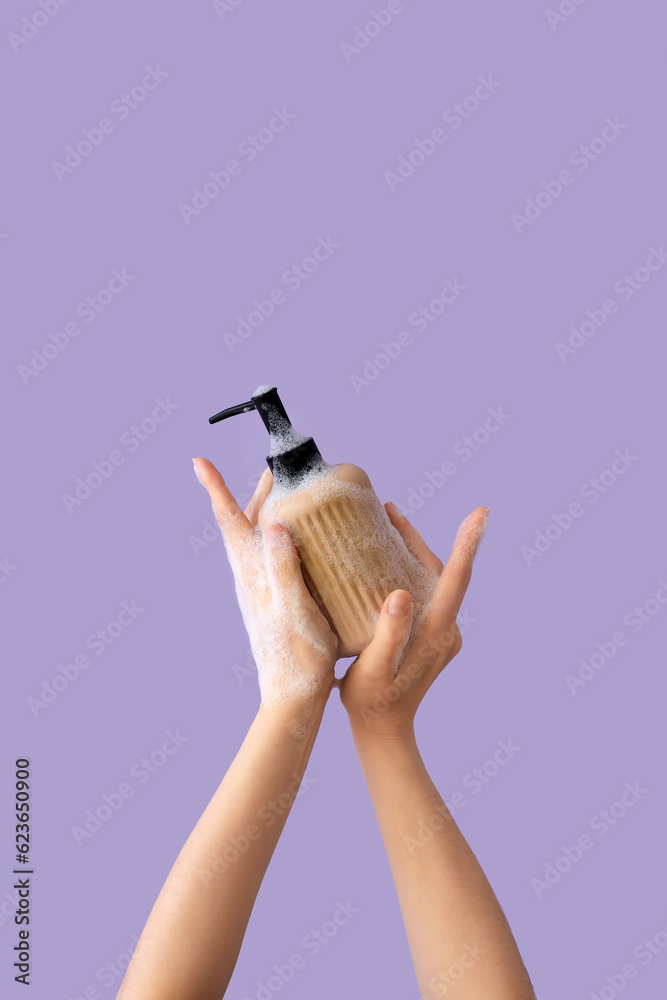 Hands with liquid soap on lilac background