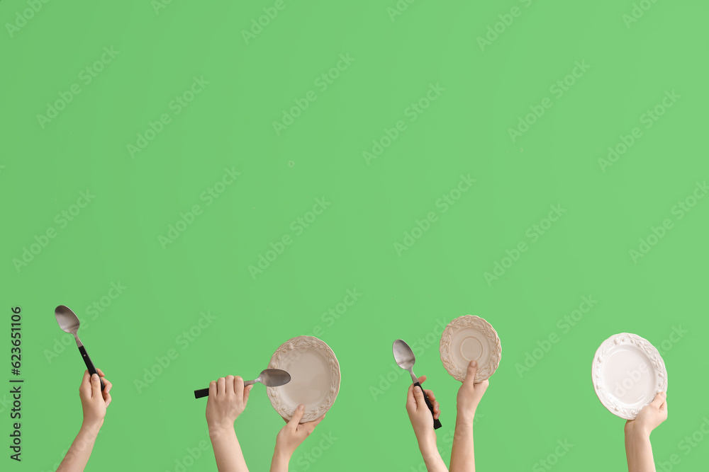 Women with plates and spoons on green background