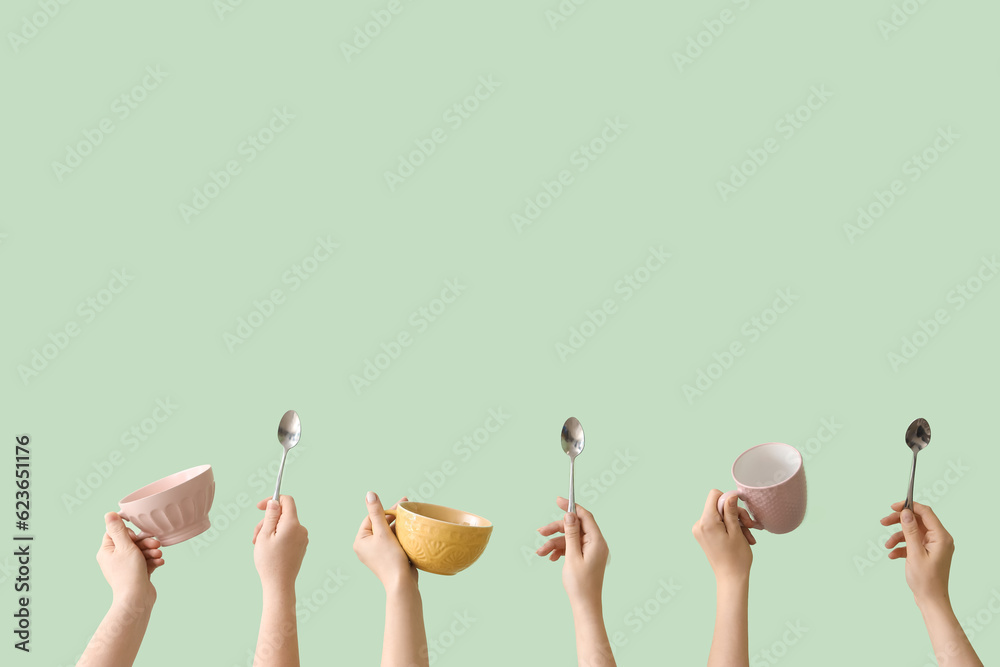 Women with mugs and spoons on green background