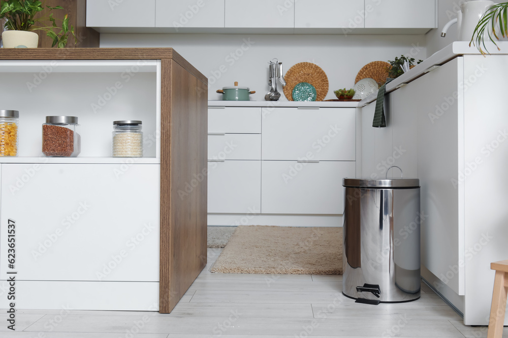 Metallic trash bin in interior of light kitchen