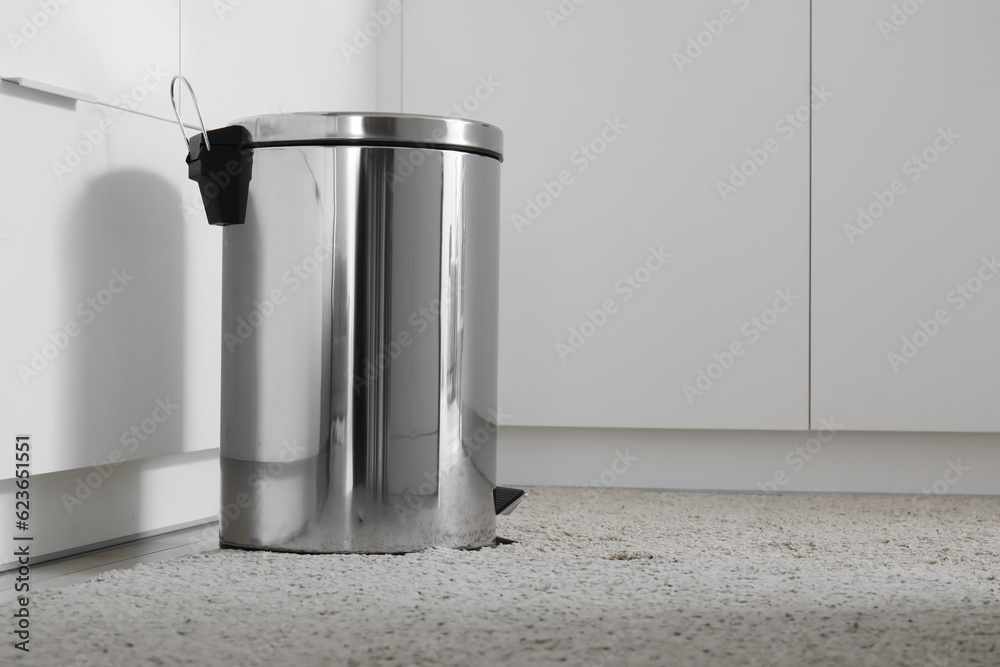 Metallic trash bin in interior of light kitchen