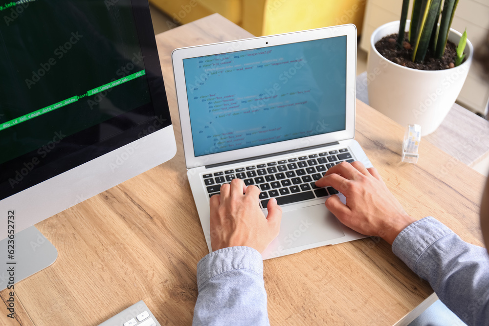 Male programmer working with laptop at table in office, closeup