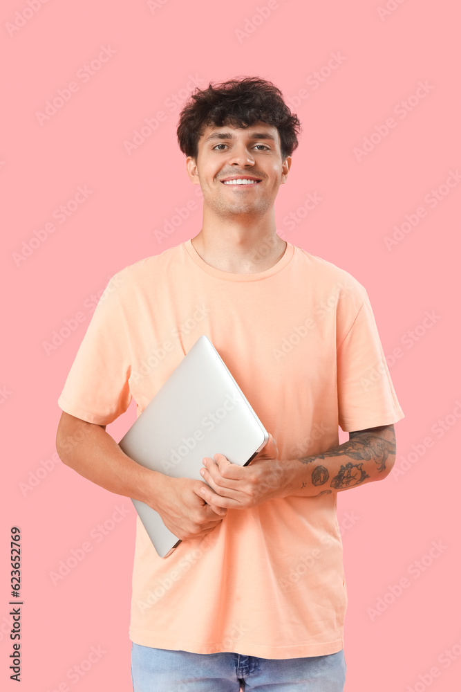 Male programmer with computer on pink background