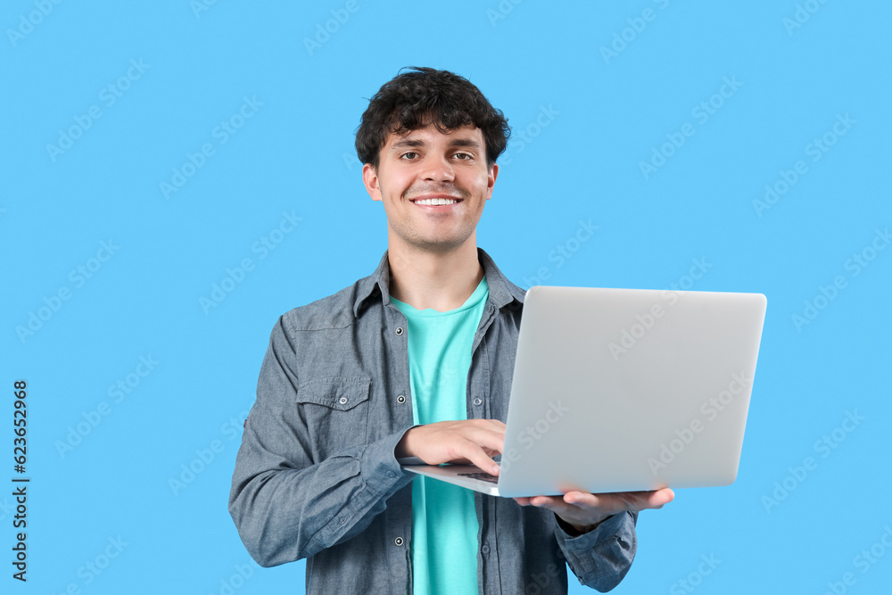 Male programmer working with laptop on blue background